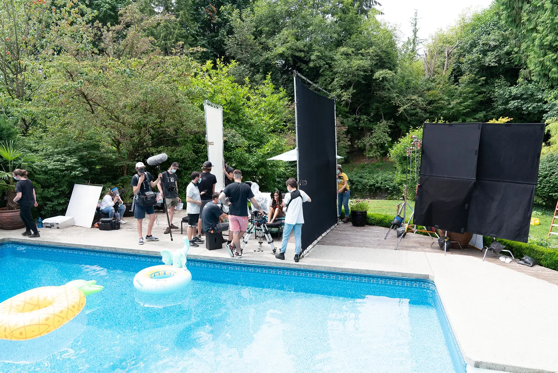 Production crew filming at a poolside location